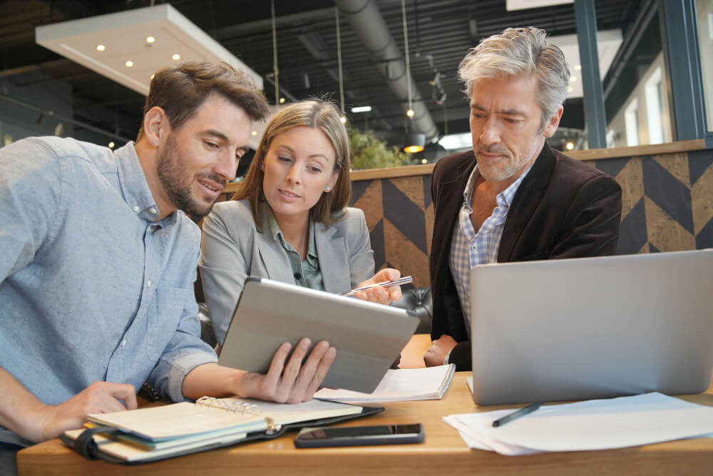 Lächelndes Team bei der Arbeit an einer Präsentation mit dem Manager