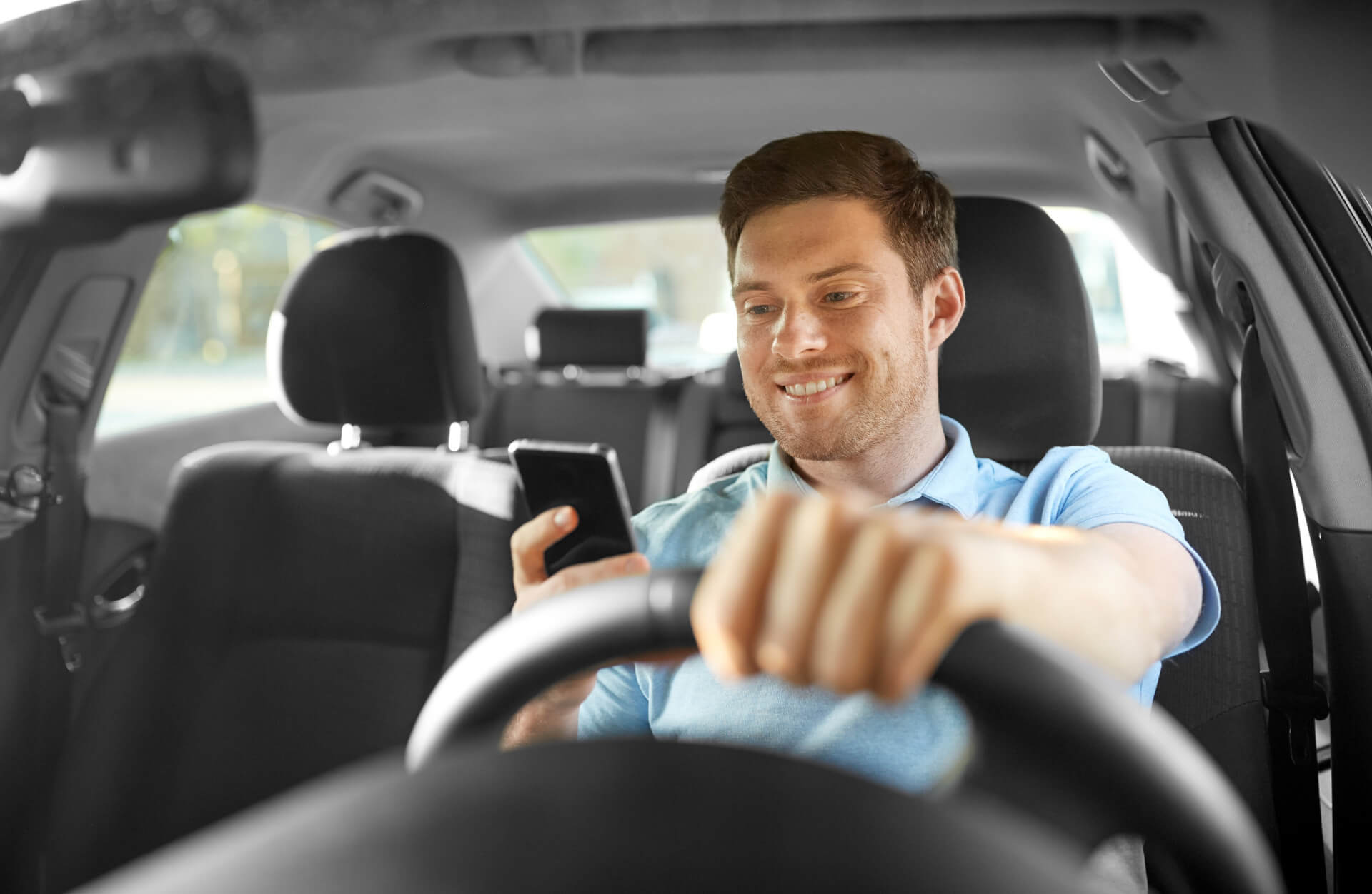 smiling man or driver driving car and using smartphone