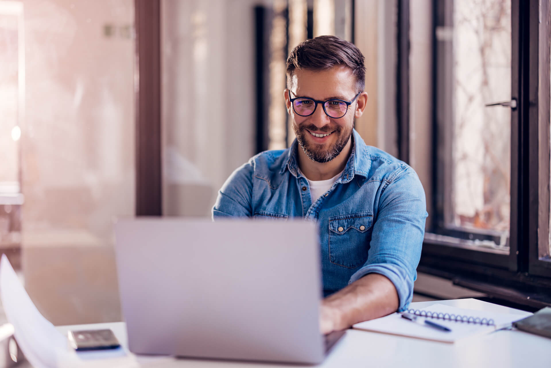 Smiling businessman sitting in office and working on laptop.